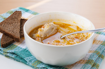 Chicken soup with pasta and brown bread on a towel  