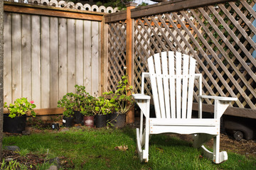 old, white, wood and empty adirondack chair in a cozy, private garden