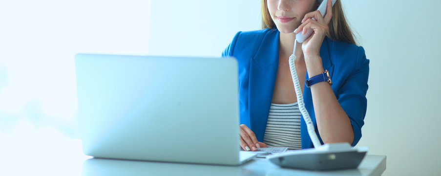 Portrait of a young woman on phone in front of a laptop computer