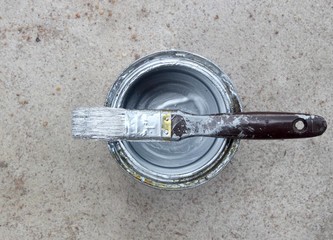 paint can on concrete with white paint and dirty paint brush