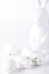 chocolate truffle eggs in white and pastel green colours; and easter bunny egg holder for Easter Day. isolated on white background with copy space, brightly lit, close up and vertical