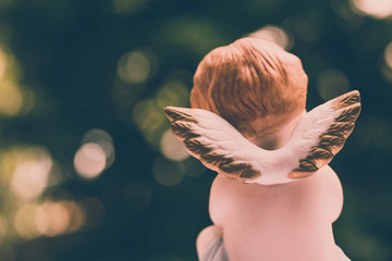 Angelic cupid statue with bokeh green garden background, valentine day or wedding, marry concept