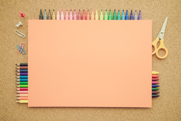 Top view of education and art supplies on cork table with empty space color paper