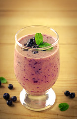 Healthy blueberry banana smoothie with mint and fresh berries in a glass