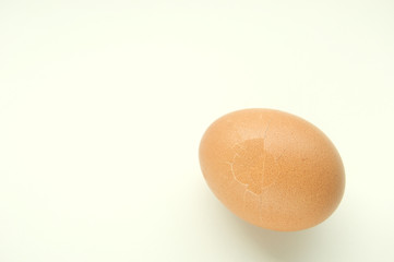 Cracked brown egg on white table