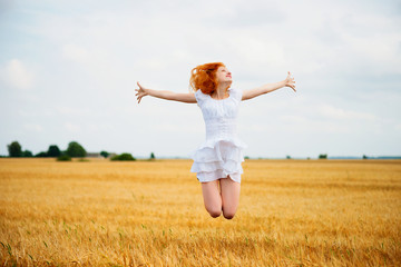 Beautiful young woman jumping at wheat field