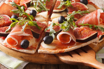 pizza with figs, ham and mozzarella macro on a board. horizontal
