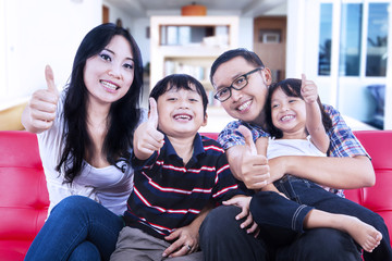 Happy family at home giving thumbs up