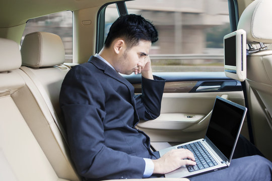 Man working with laptop inside a car