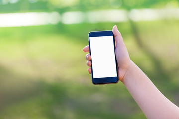 Hand holding smart mobile phone on wooden table and light blurre