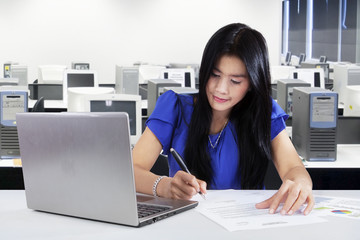 Woman writing on document in office