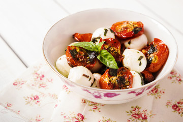 Salad of roasted cherry tomatoes with mozzarella and basil sauce. Selective focus  