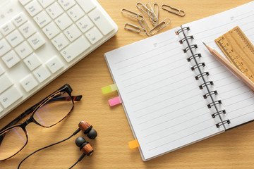 Notebook on wooden table, top view.