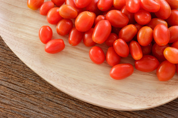 Fresh cherry tomato on wooden plate.