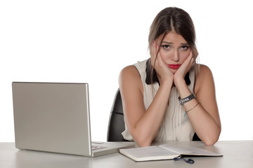 Young and worried beautiful woman with laptop and notebook