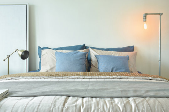 Industrial style reading lamp and blue pillows on modern style bedding