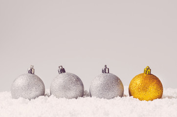 silver and golden decorative christmas balls on snow against grey background