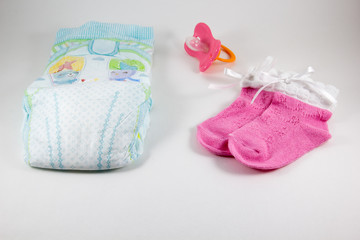 Pacifier, booties, baby diaper on a white background