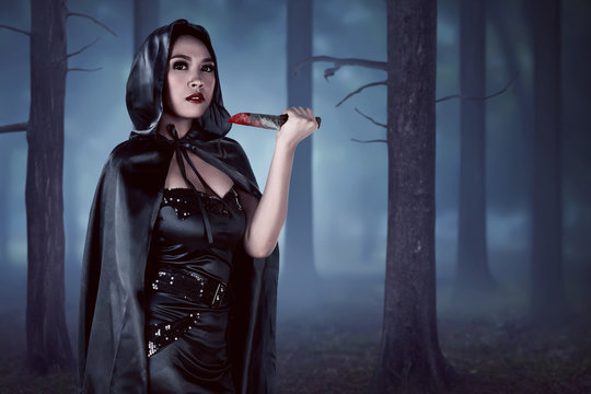 Asian witch woman holding knife in forest