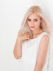 Beautiful blue-eyed blonde with pensive look. Portrait of beautiful thoughtful young woman on white...