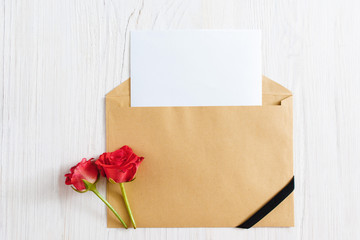 Opened envelope with blank paper and black ribbon with two roses, flat lay. Mourning, funeral, sorrow concept