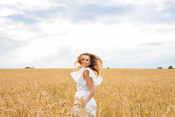 Naklejka premium Happy woman jumping in golden wheat