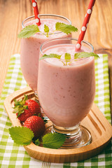 Healthy tasty milk cocktails with strawberries on brown wooden background.
