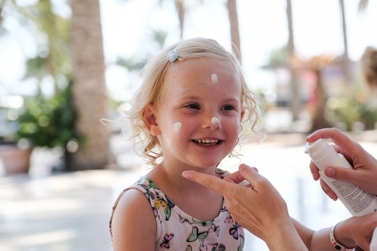 kleines blondes M&auml;dchen beim auftragen von sonnencreme