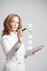Young business woman checking on checklist box. Gray background.