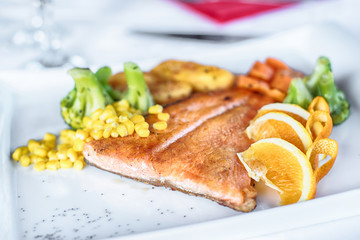 Grilled salmon with spring vegetables on white plate