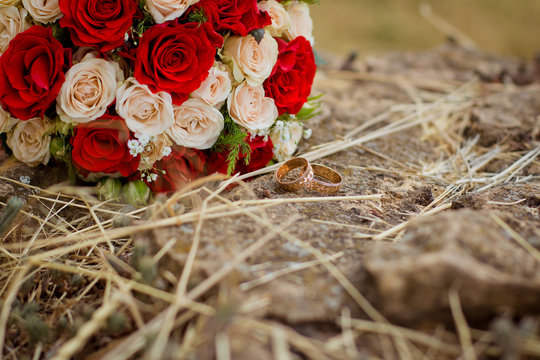 Wedding rings near bouquet of roses