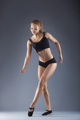 Fototapeta na wymiar Young beautiful dancer posing on a studio background