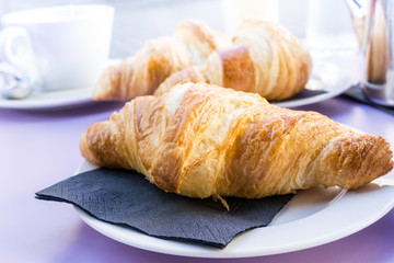 Breakfast with coffee and croissants in a basket on table
