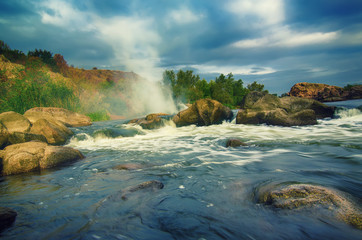Mountain fast flowing river stream of water in the rocks with dark blue sky and fog
