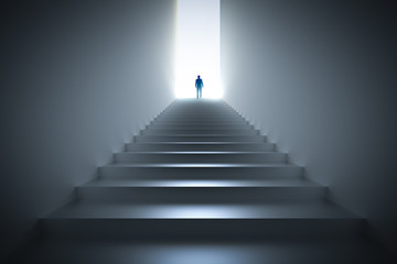 Businessman climbing the stairs towards light.