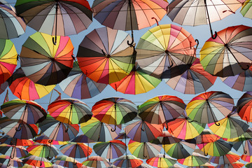 Fototapeta na wymiar Decoration with hanging umbrellas coloring the sky over city street