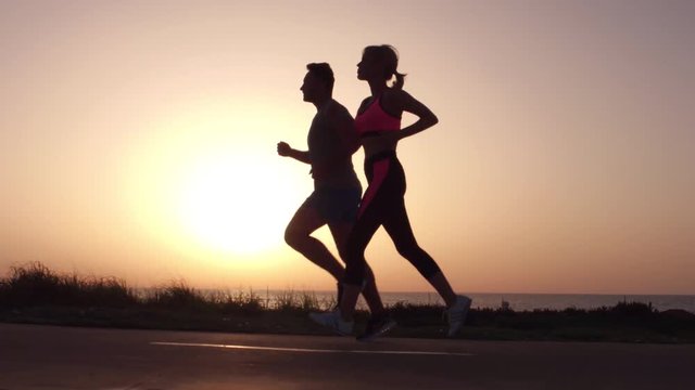 Running sport athletes woman and man jogging at night sunset.