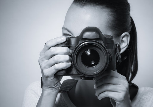 Female photographer holding camera DSLR. 