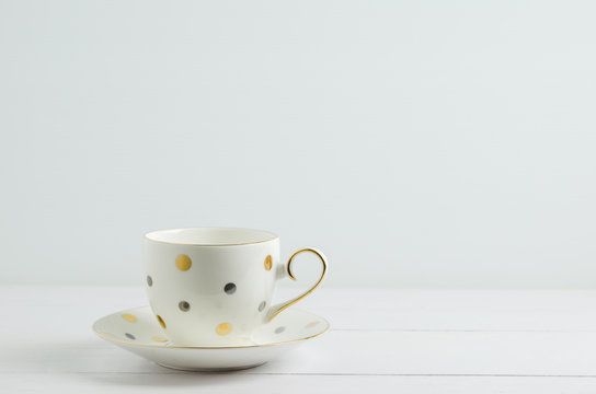 Vintage coffee cup with cute dot pattern on white wooden backgro