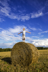 Obraz premium Smiling boy on a haystack on the background of blue sky