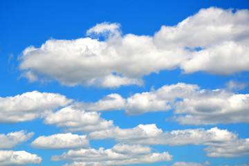 Naklejka na ściany i meble Fluffy white clouds diminishing towards the horizon on a sunny day in bright blue sky