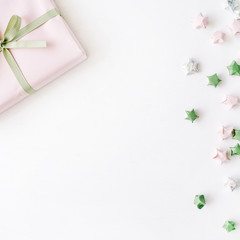 pink gift box with ribbon and bow on white decorated with tinsel background. flat lat, top view