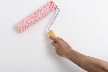 Close up of painter arm painting a wall with red paint roller