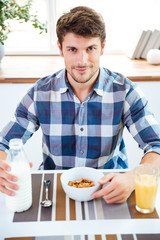 Fototapeta na wymiar Man sitting and eating cereals with milk on the kitchen