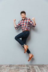 Happy excited cheerful young man jumping and celebrating success