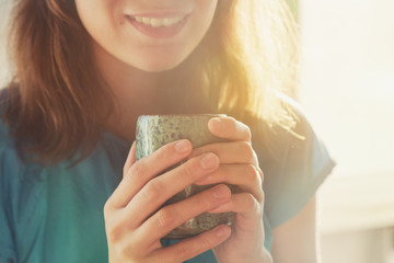 girl drinking cup of coffee or tea in morning sunlight