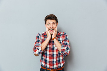 Surprised excited man in plaid shirt standing with mouth opened