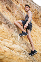 Young man climbing a steep wall in mountain