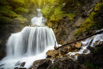 Amazing mountain waterfall near Farchant village at Garmisch Partenkirchen district with sunlight flanking trees of alpine forrest, Farchant, Bavaria, Germany. - 118809705