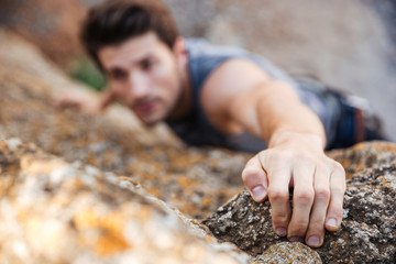 Man reaching for a grip while he rock climbs